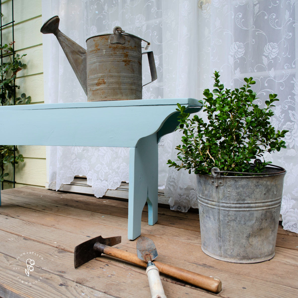 victorian farmhouse garden bench on wood porch with rusty watering can and bucket with foliage plant, garden tools at the bast