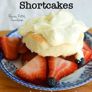 homemade shortcake with fresh strawberries, blueberries and topped with whipped cream, with text overlay Buttermilk Strawberry shortcakes, flower patch farmhouse