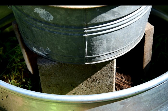 galvanized tub balanced on concrete pavers, DIY planter with solar fountain