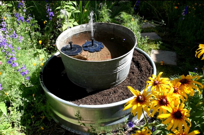 galvanized tub with solar fountains on top of a soil filled fire ring planter