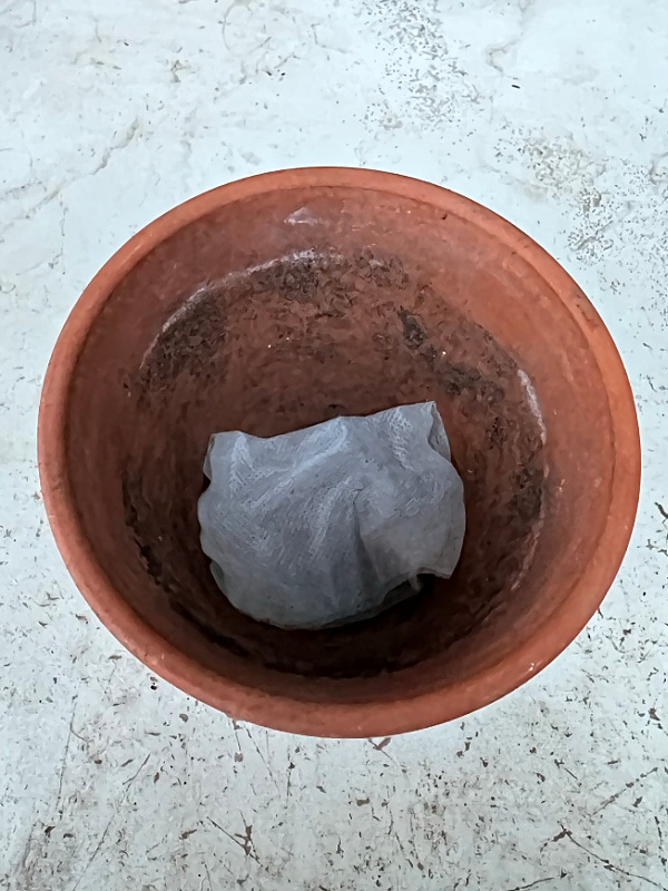 filter placed over drainage hold of a terra cotta pot