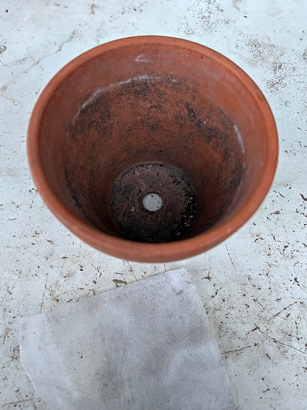 terra cotta pot on white surface, drainage hold