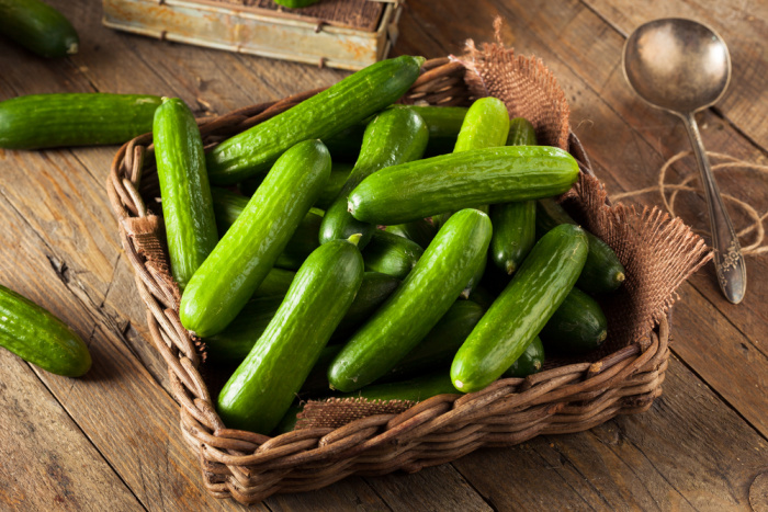 mini cucumbers in a basket on a wooden table