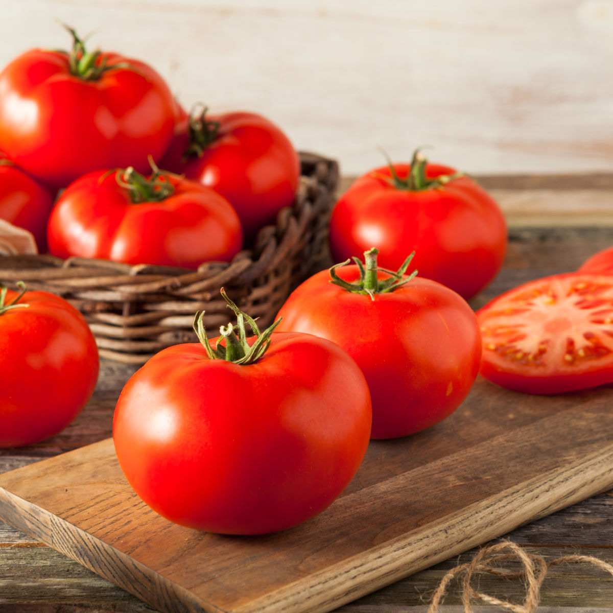 Raw Organic Red Beefsteak Tomatoes Ready for Cooking, basket filled with tomatoes in background and some sliced to the right