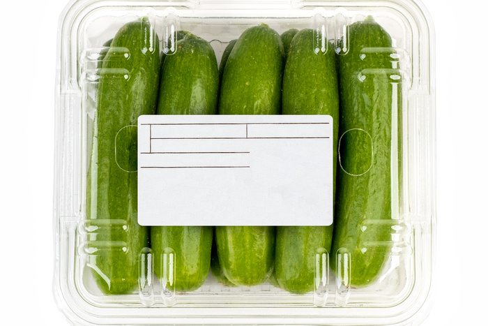 Freshly harvested mini cucumber with package and label on white background