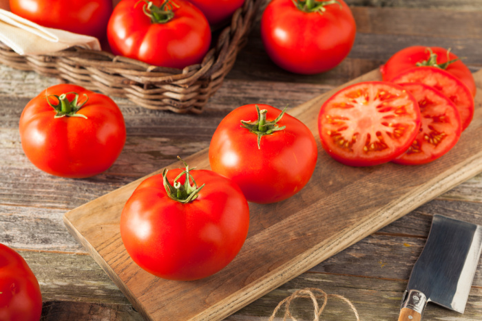 Raw Organic Red Beefsteak Tomatoes Ready for Cooking sitting on a wood board with slicing knife next to it