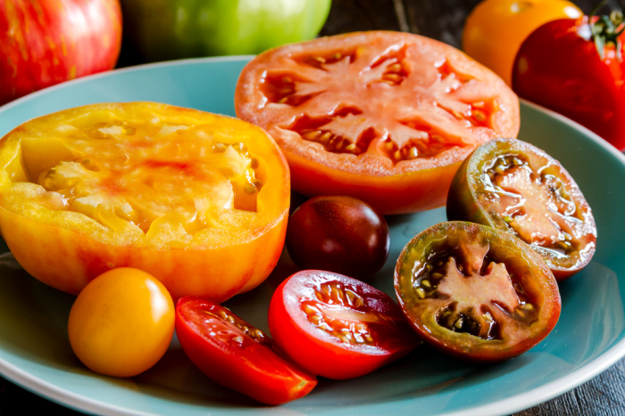 Varieties of sliced heirloom tomatoes sitting on light blue plate