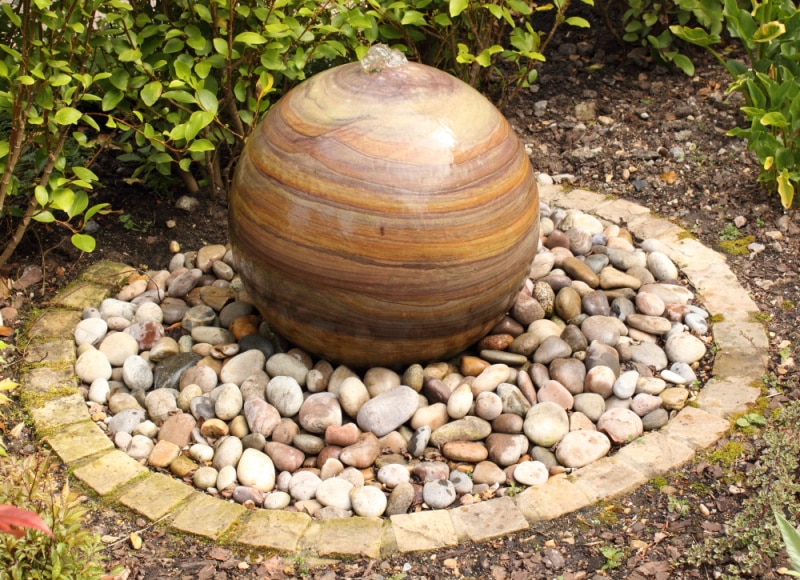 bubbling water fountain, water spilling over orb and into stones, pondless.