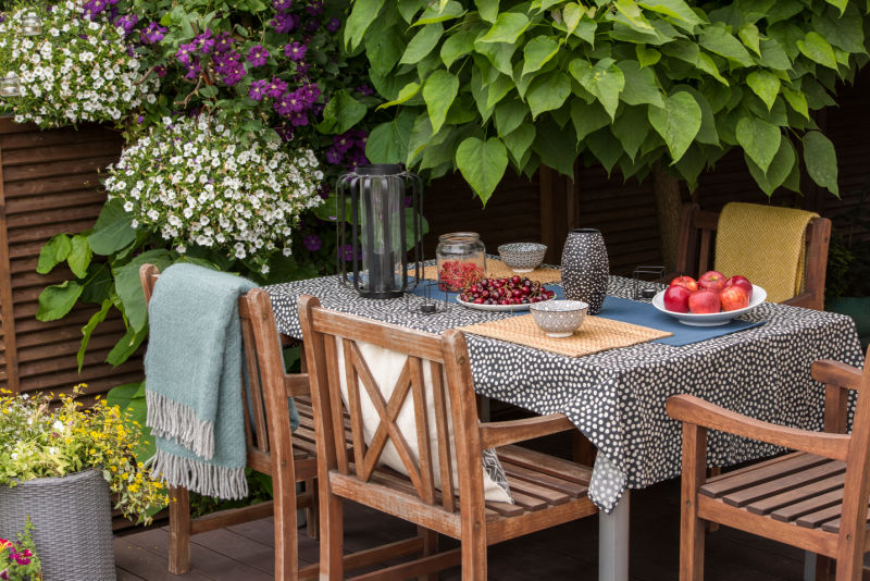 Dining table and chairs with polka dot pattern table cloth outdoors with flowers and trees