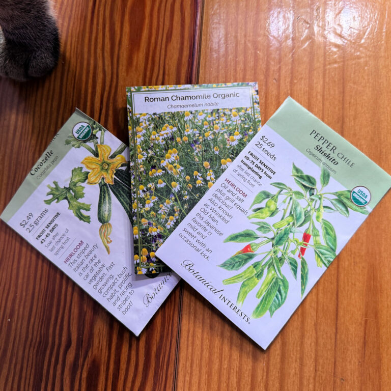 Packets of organic seeds lying fanned out on a wood surface